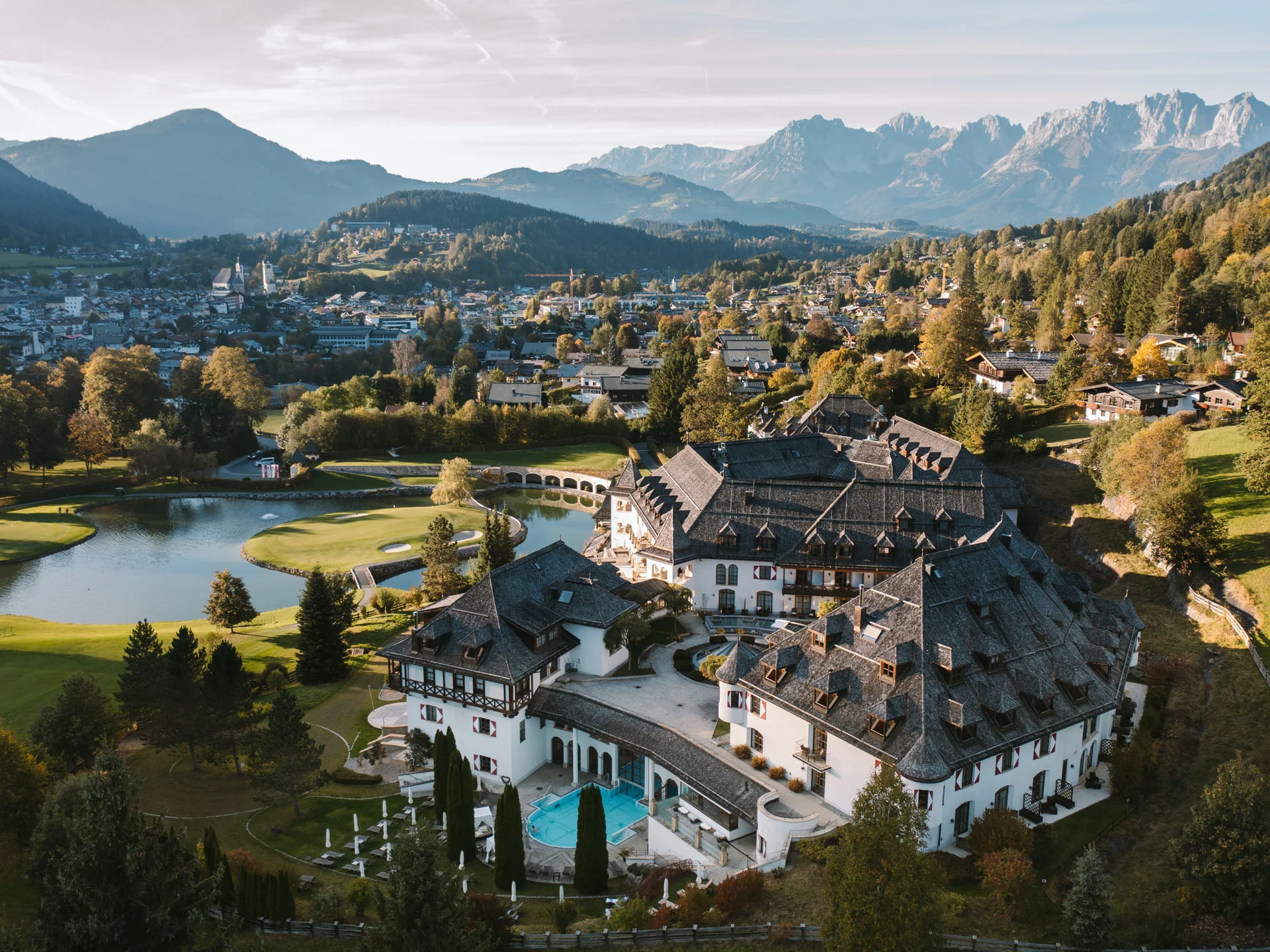 Bilder, die Sie sehen müssen. Luftaufnahme eines Hotels in den Bergen mit Golfplatz und Dorf im Hintergrund