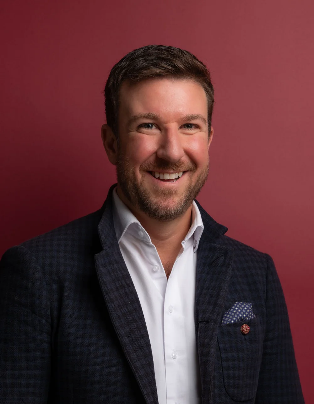 Was zählt, sind die Menschen. Lächelnder Mann in weißem Hemd und dunklem Sakko vor rotem Hintergrund