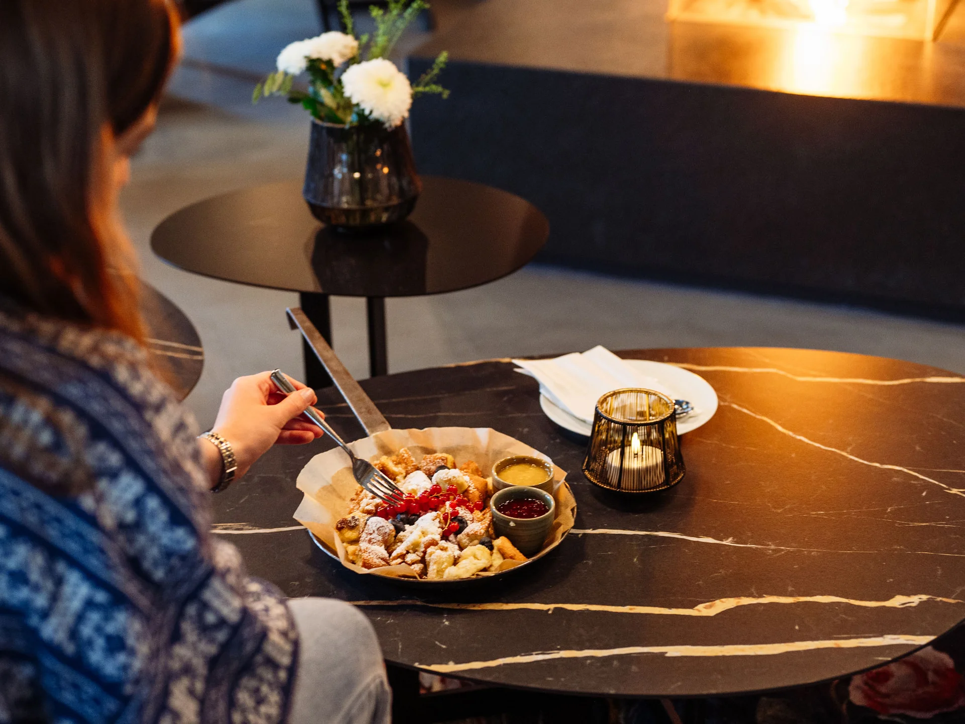 Bilder, die Sie sehen müssen. Person isst mit Gabel an einem Tisch mit Dessert und Kerze