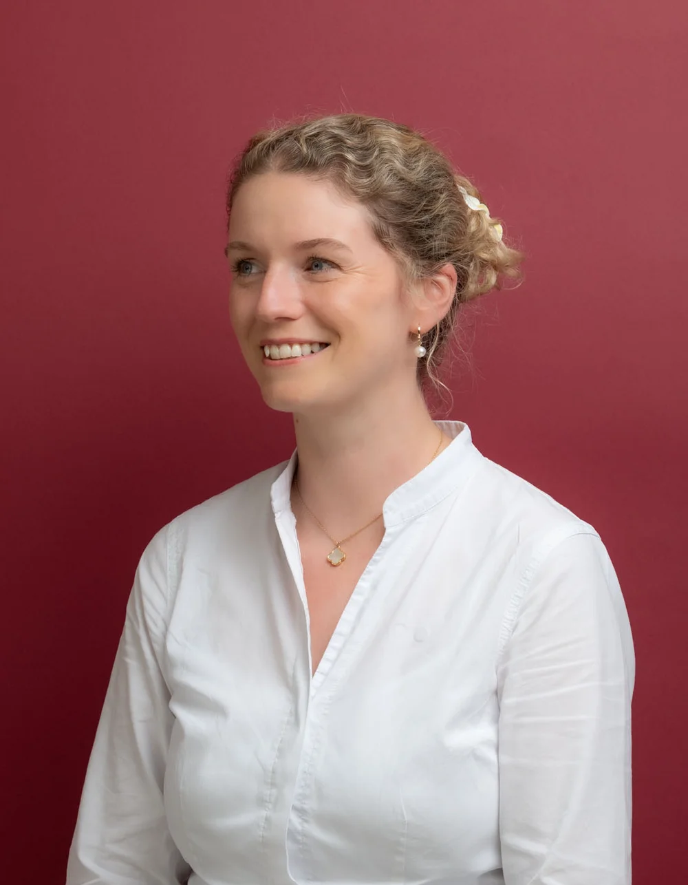 Was zählt, sind die Menschen. Lächelnde Frau mit weißer Bluse vor rotem Hintergrund