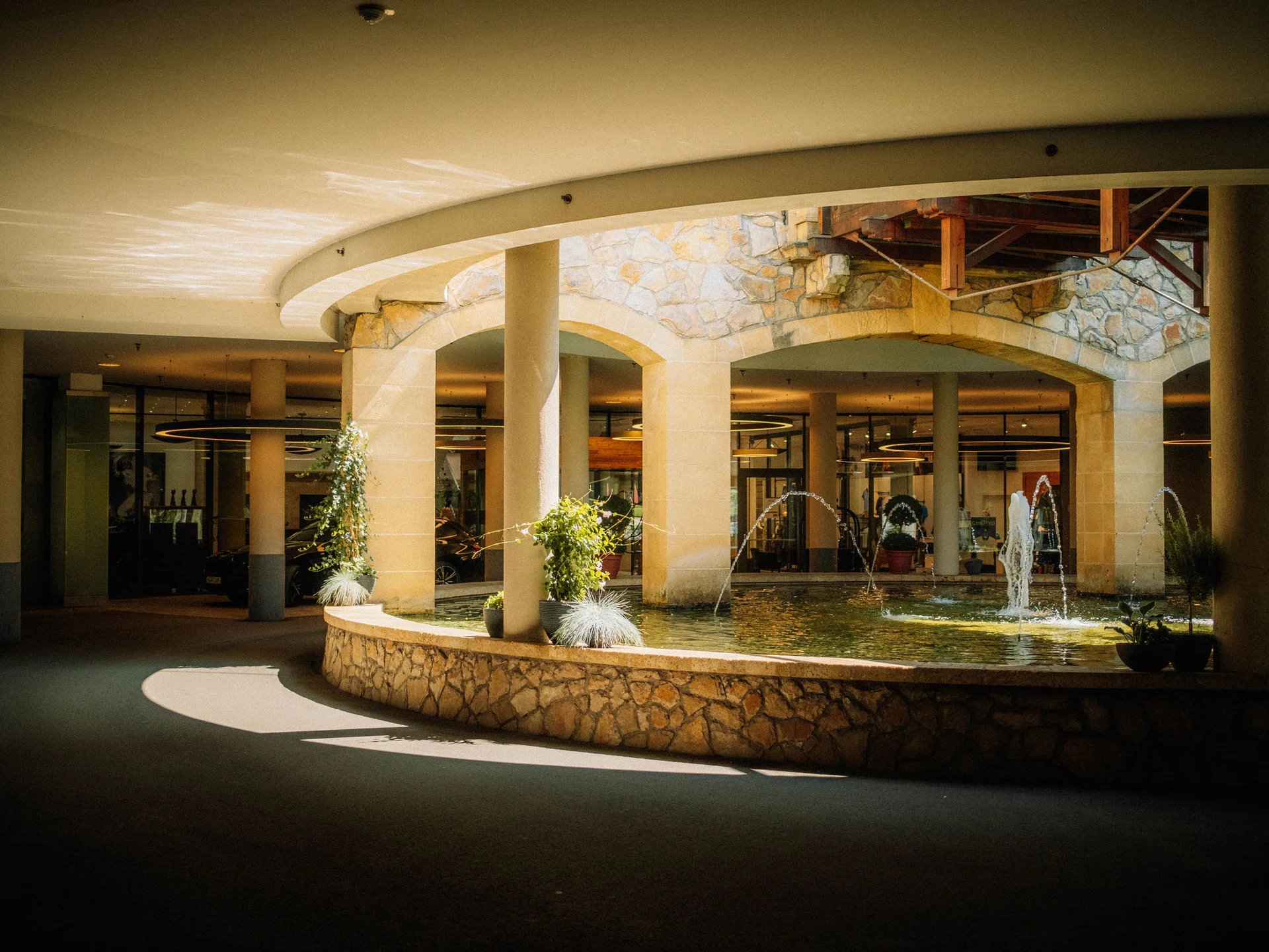 Bilder, die Sie sehen müssen. Überdachter Bereich mit steinerner Brunnenumrandung und springenden Wasserfontänen