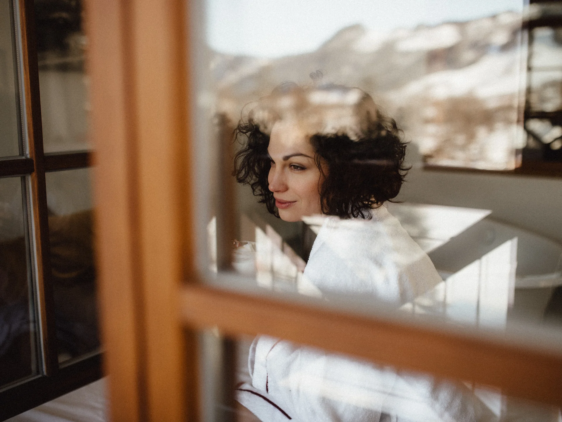 Bilder, die Sie sehen müssen. Frau in weißem Bademantel sieht nachdenklich aus dem Fenster