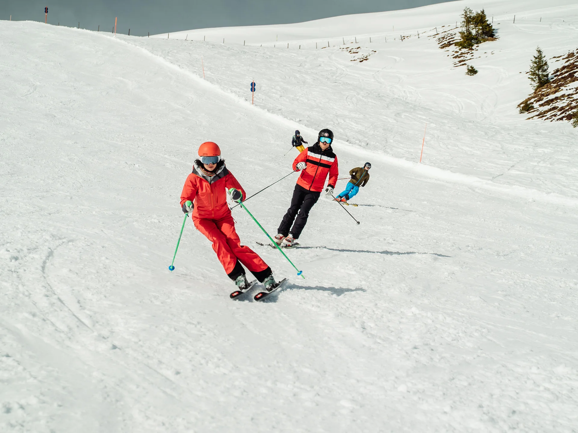 Bilder, die Sie sehen müssen. Mehrere Skifahrer in roter und blauer Kleidung auf einer schneebedeckten Piste