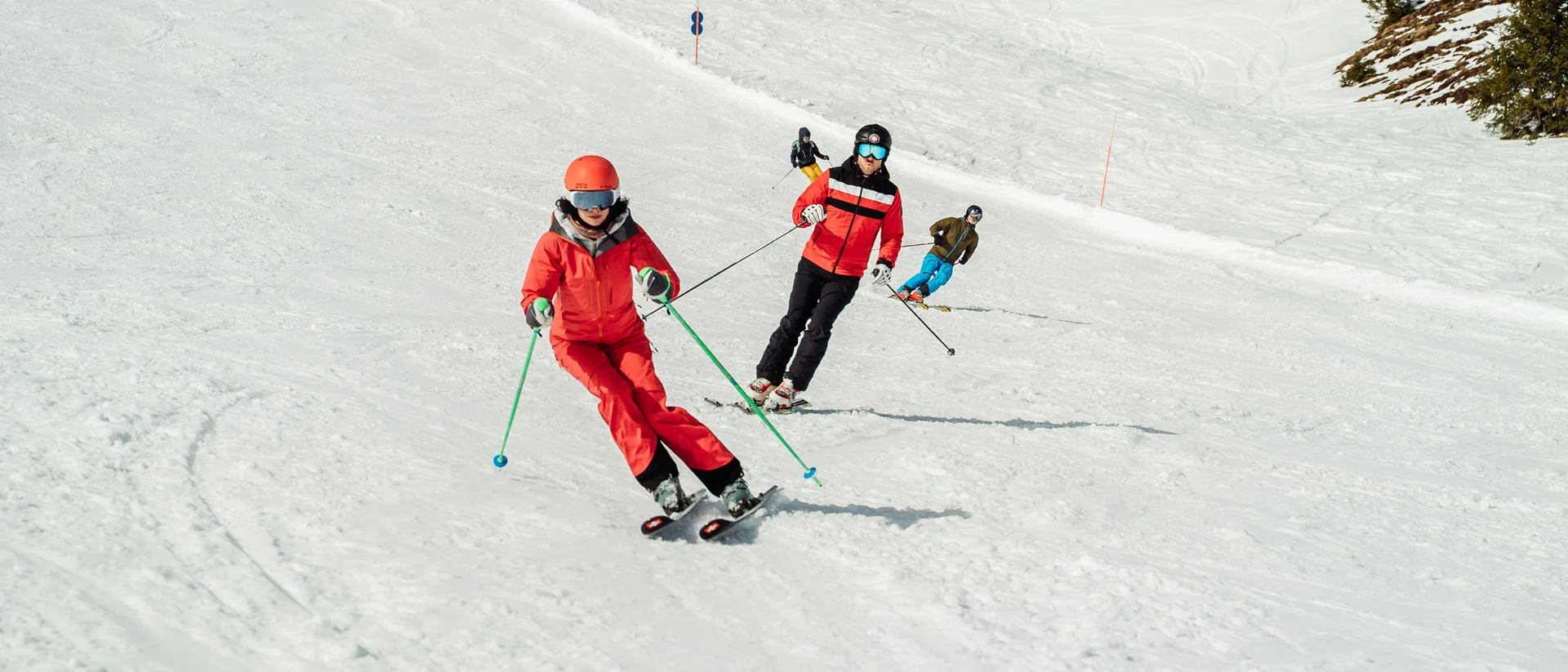 Ein ganzes Jahr in Bewegung Mehrere Skifahrer in roter und blauer Kleidung auf einer schneebedeckten Piste
