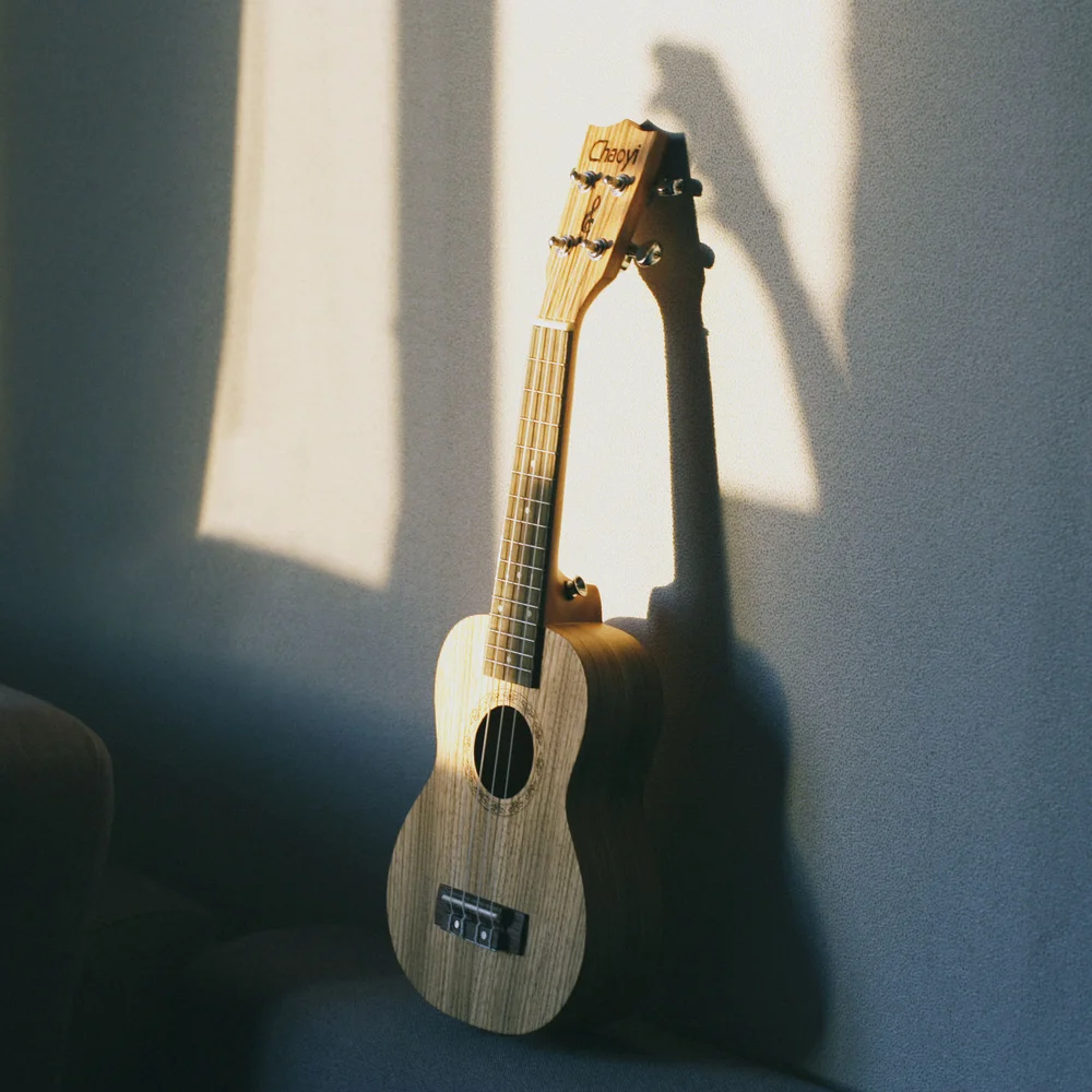 Kulturhotel. Schlosshotel. Kitzbühel. Ukulele lehnt an grauer Wand im Sonnenlicht