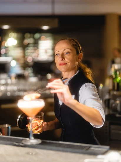 Silvester in Kitzbühel = Hotel, Party, Champagner Bartenderin bereitet einen Cocktail in einer Bar zubereitet