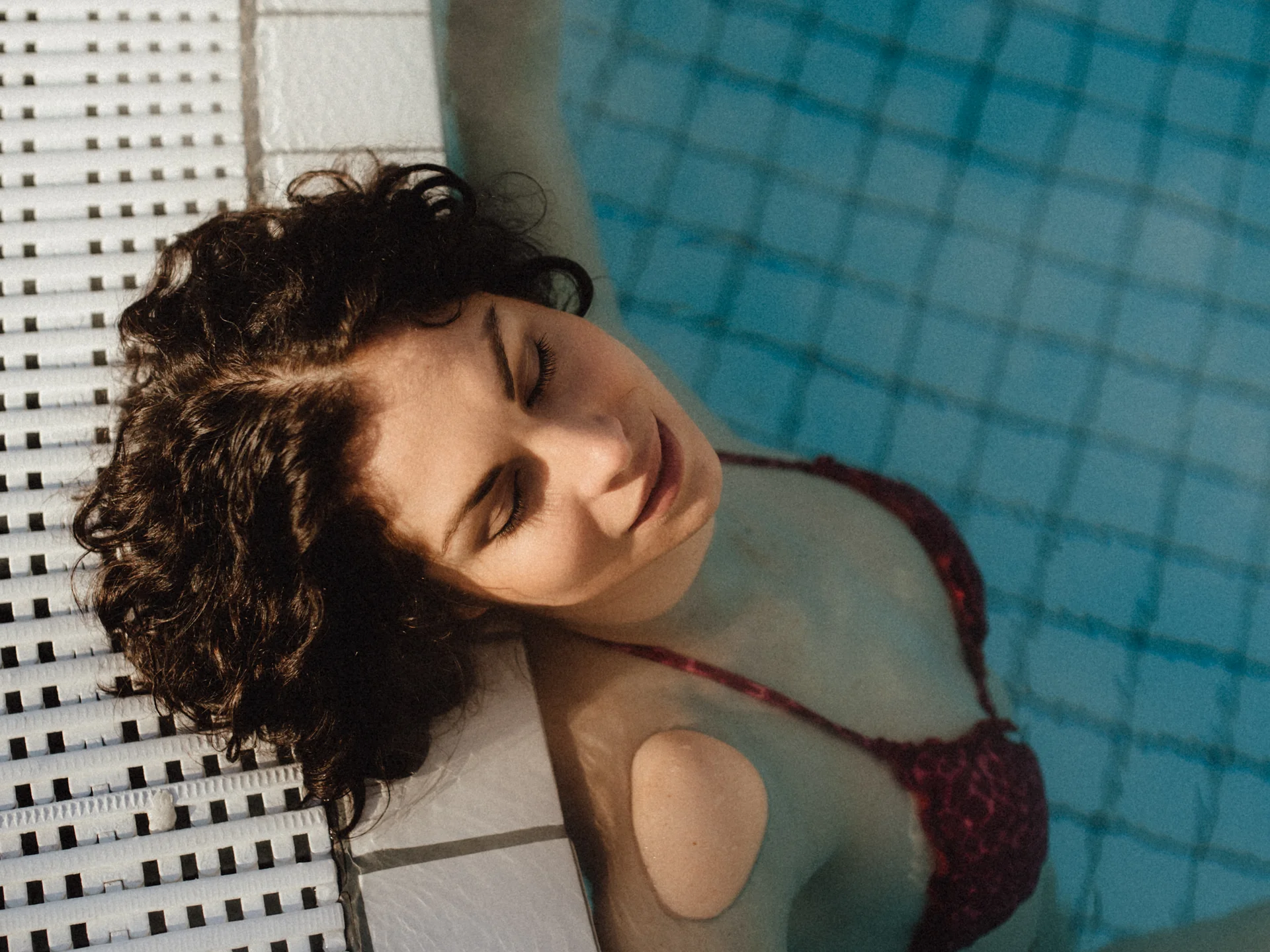 Bilder, die Sie sehen müssen. Frau entspannt sich im Pool an der Schwimmbeckenmauer