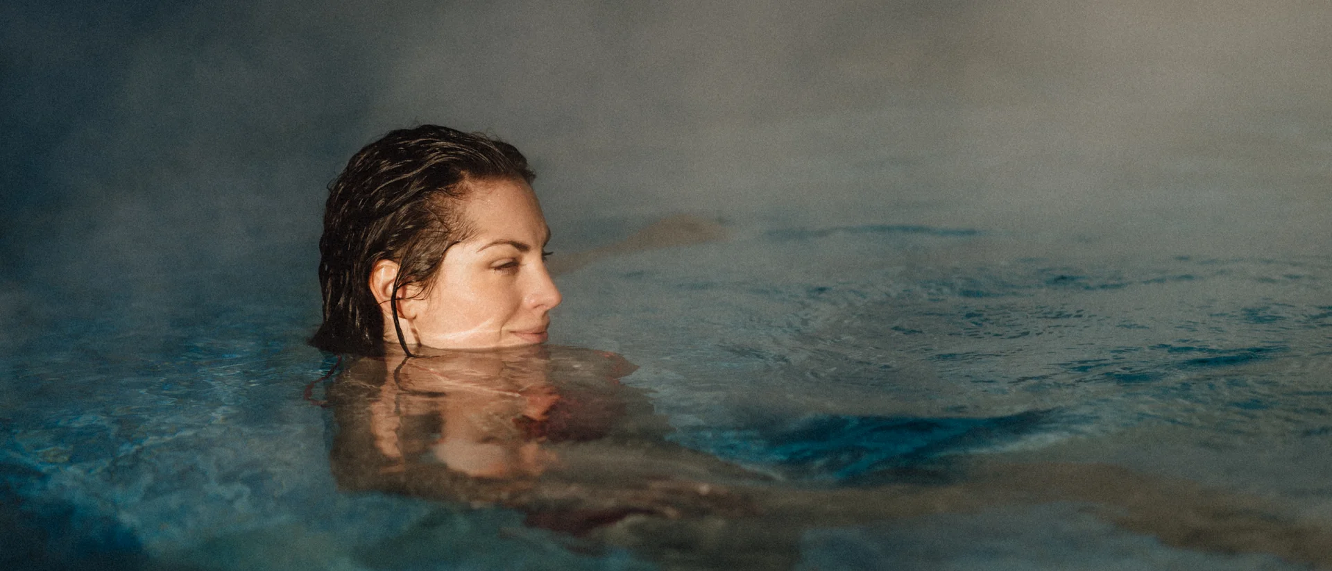 Premium-Spa im Wellnesshotel in Kitzbühel Frau entspannt sich im dampfenden Wasser