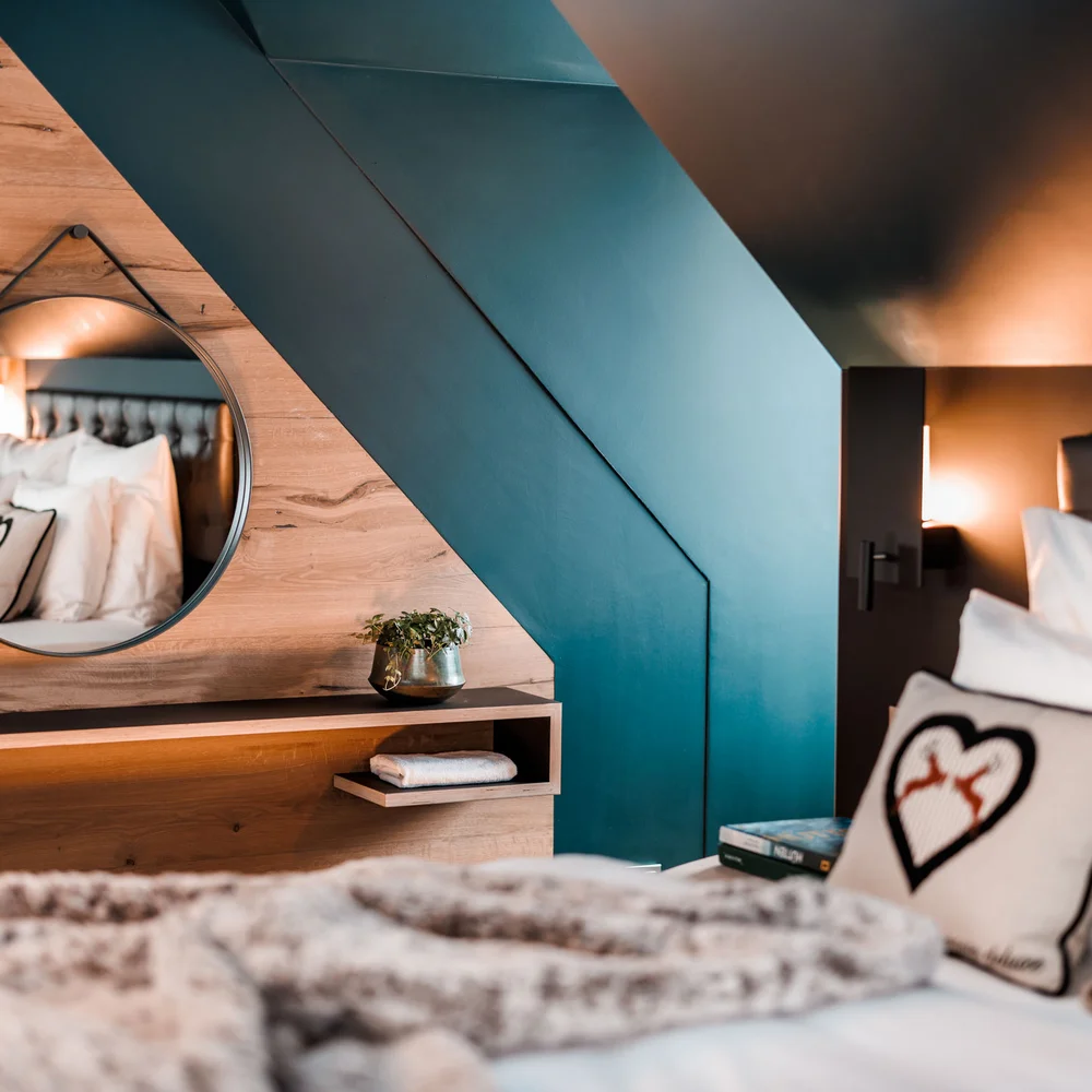 Eine der schönsten Hochzeitslocations in Tirol Gemütliches Schlafzimmer mit rundem Spiegel und Herz-Kissen