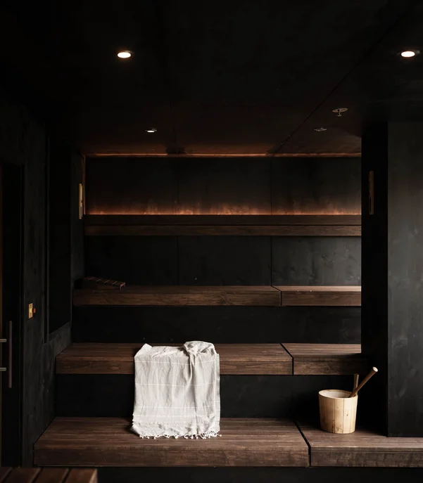 Premium-Spa im Wellnesshotel in Kitzbühel Moderner dunkler Saunaraum mit Holzbänken und Saunakübel