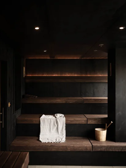 In Kitzbühel ein Hotel mit Pool, bitte. Moderner dunkler Saunaraum mit Holzbänken und Saunakübel