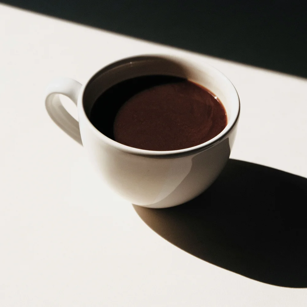 So schön: Kitzbühel-Urlaub mit Kindern Weiße Tasse mit dunkler Schokolade vor Schwarz-Weiß-Hintergrund