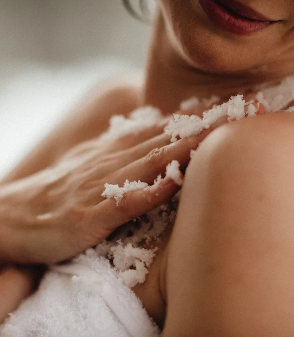 Premium-Spa im Wellnesshotel in Kitzbühel Frau cremt ihre Schulter mit Körperpeeling im Badezimmer ein