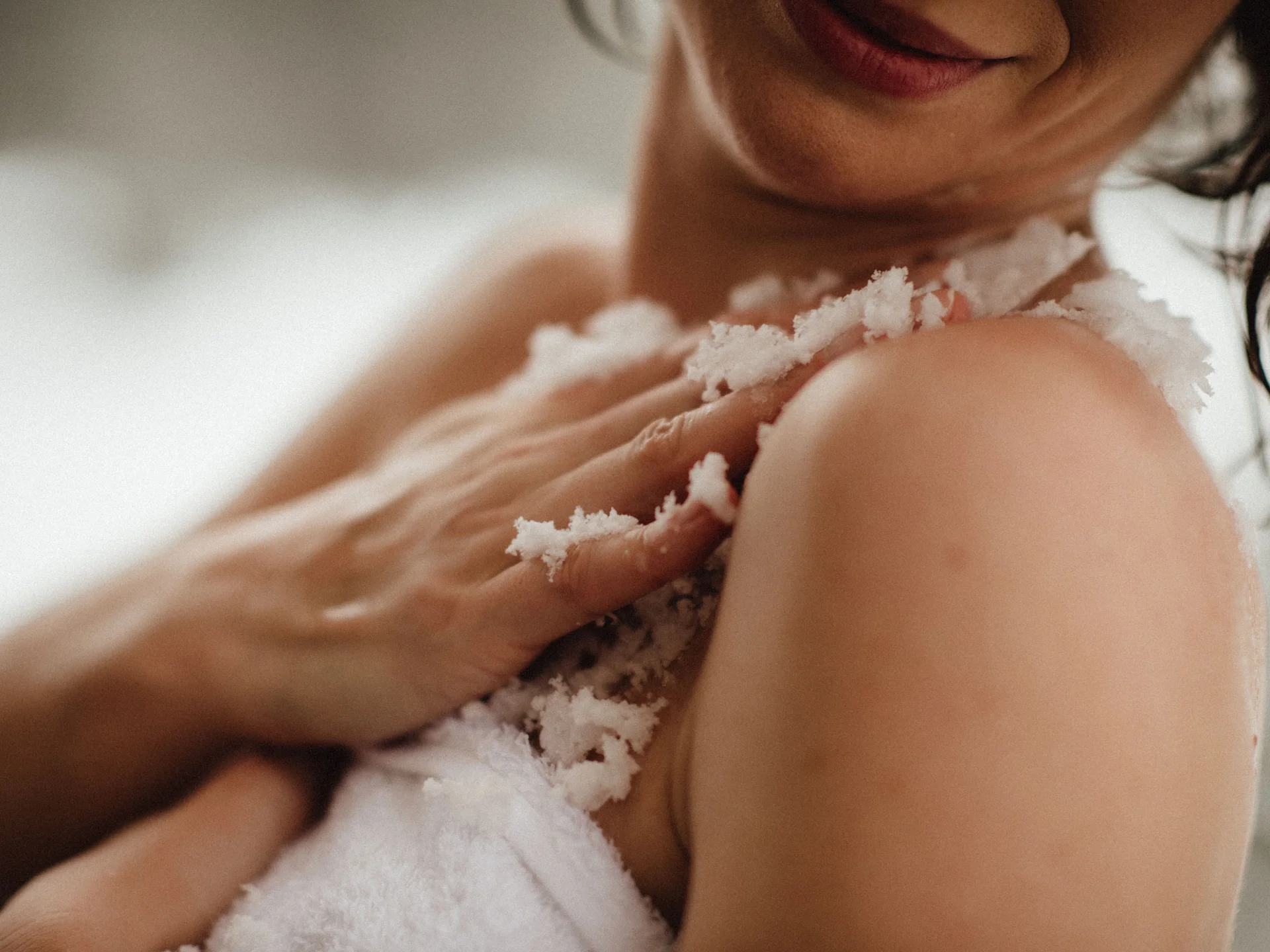 Bilder, die Sie sehen müssen. Frau cremt ihre Schulter mit Körperpeeling im Badezimmer ein