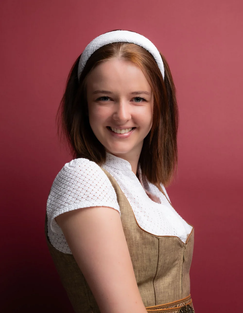 Was zählt, sind die Menschen. Junge Frau in traditionellem Dirndl vor rotem Hintergrund