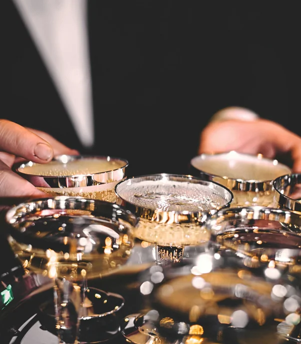 Silvester in Kitzbühel = Hotel, Party, Champagner Person serviert silberne Cocktailgläser mit Getränken auf einem Tablett