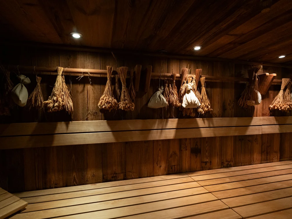 Bilder, die Sie sehen müssen. Holzsauna mit Bündeln aus getrockneten Kräutern und Lichtspots