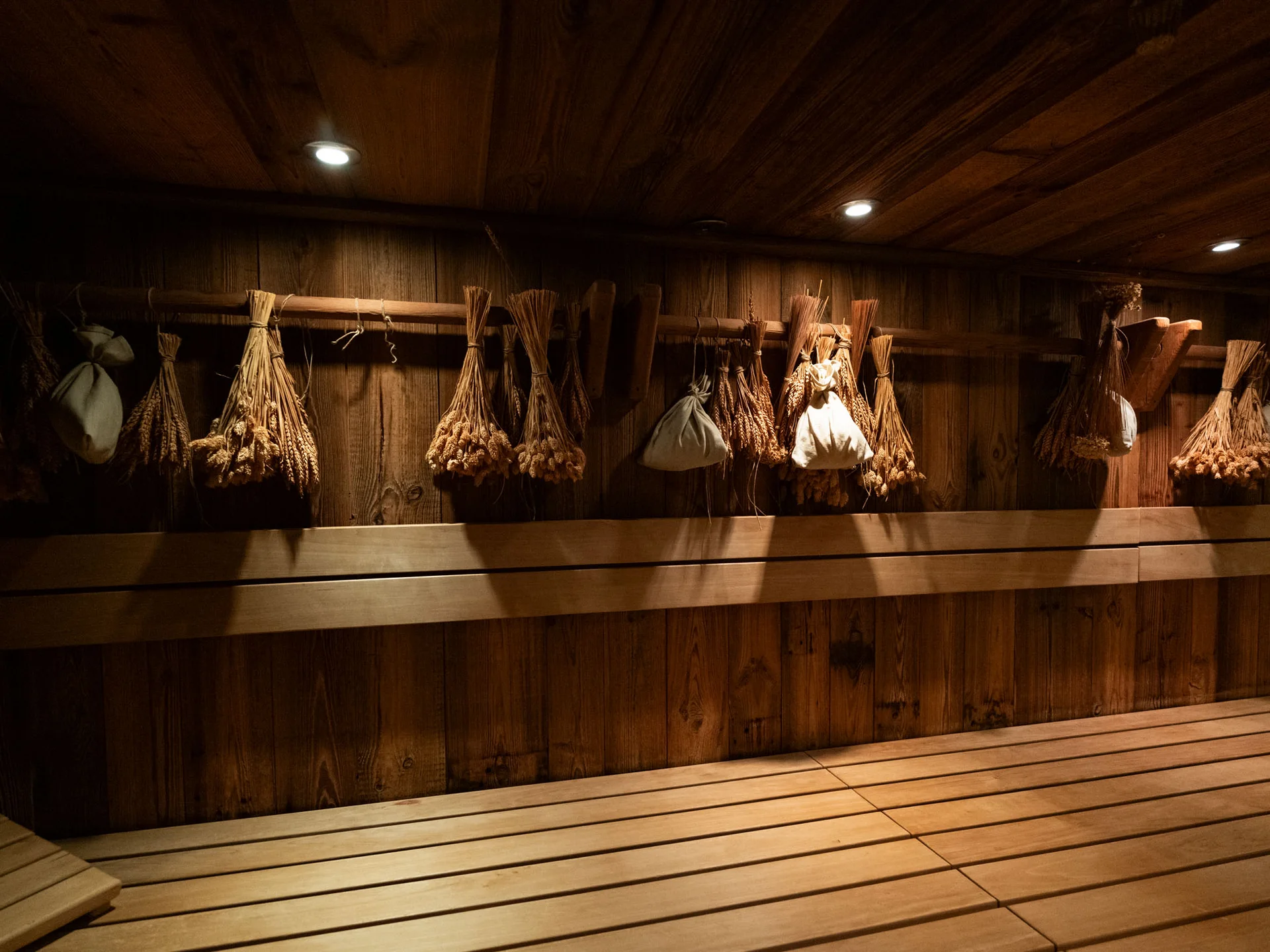 Bilder, die Sie sehen müssen. Holzsauna mit Bündeln aus getrockneten Kräutern und Lichtspots