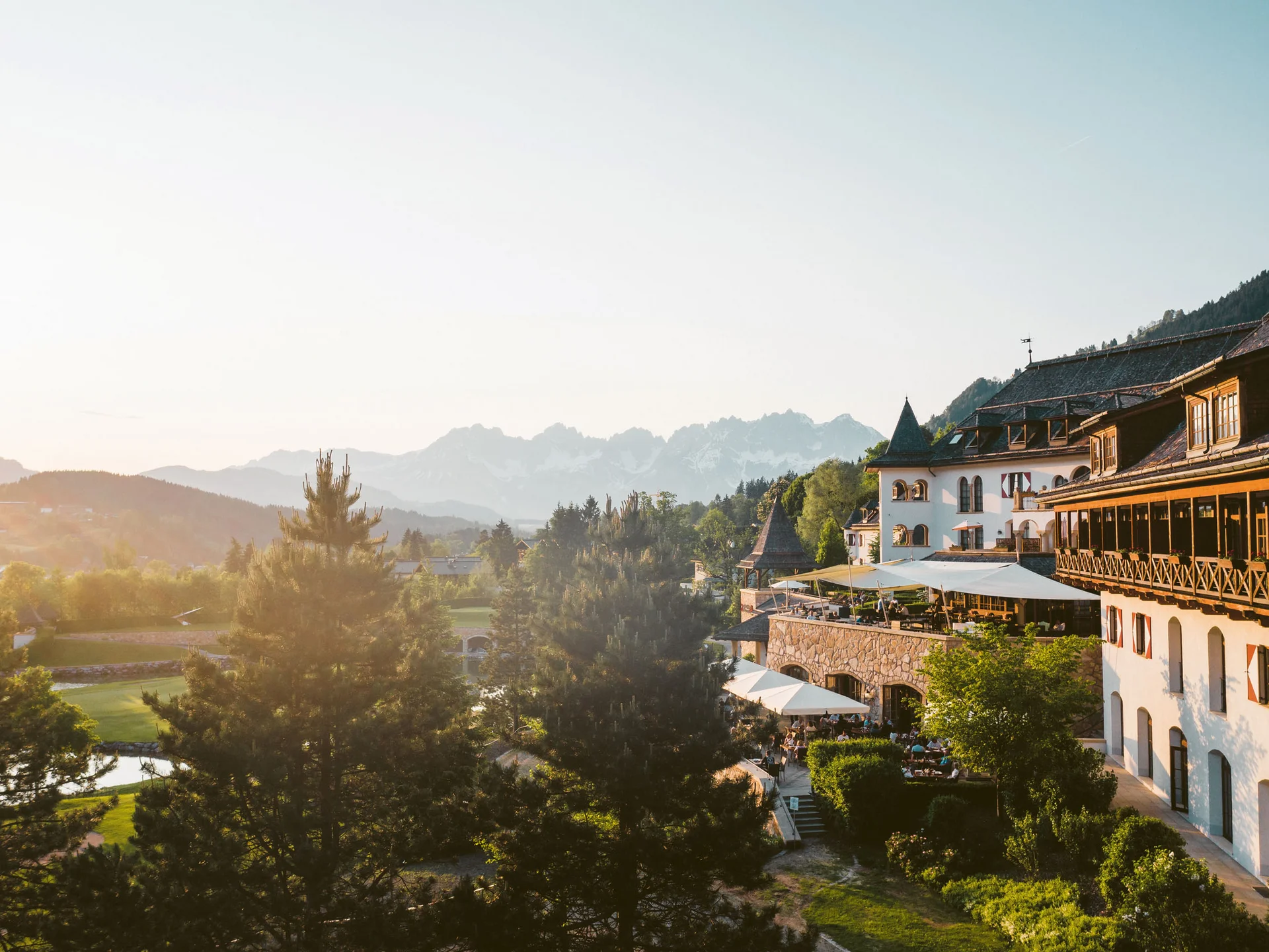 Bilder, die Sie sehen müssen. Blick auf ein altes Hotel mit Terrasse und Berglandschaft im Sonnenuntergang