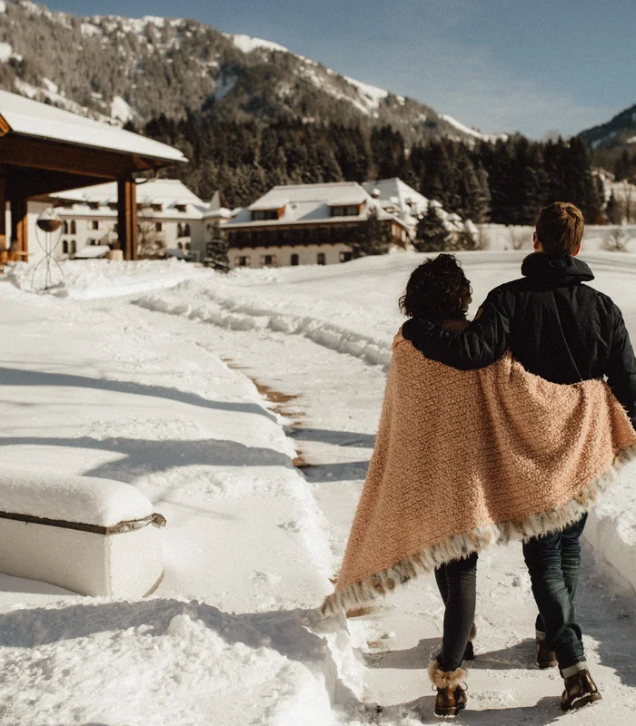 Ausflugsziele & Sehenswürdigkeiten rund um Kitzbühel Paar geht ausgestreckt durch schneebedeckten Weg in den Bergen