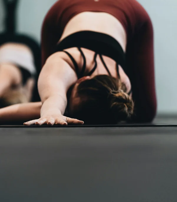 Fitness und Yoga im Hotel in Tirol Frau macht Yoga-Übung Child's Pose auf Matte im Fitnessstudio