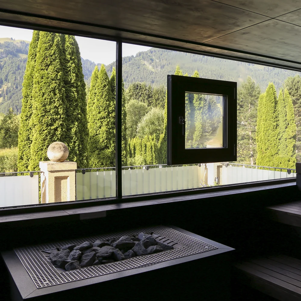 Premium-Spa im Wellnesshotel in Kitzbühel Moderner Sauna Innenraum mit Blick auf Berge und grüne Bäume