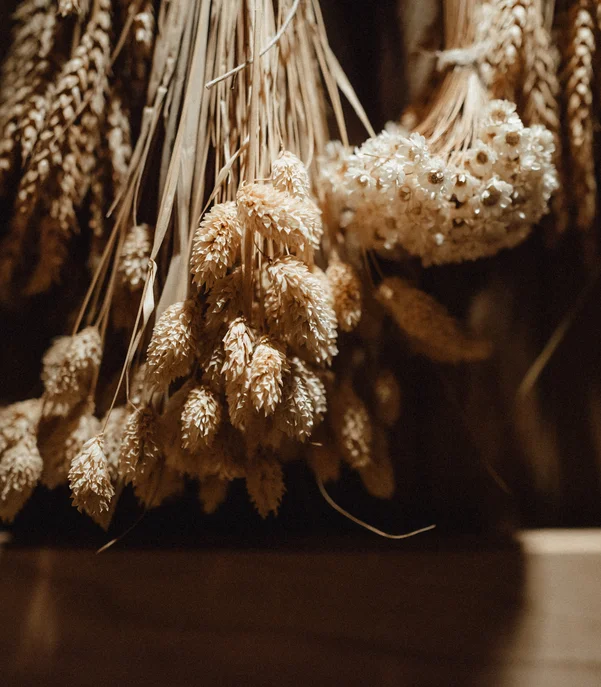 Premium-Spa im Wellnesshotel in Kitzbühel Getrocknete Ähren und Blumen hängen in warmem Licht