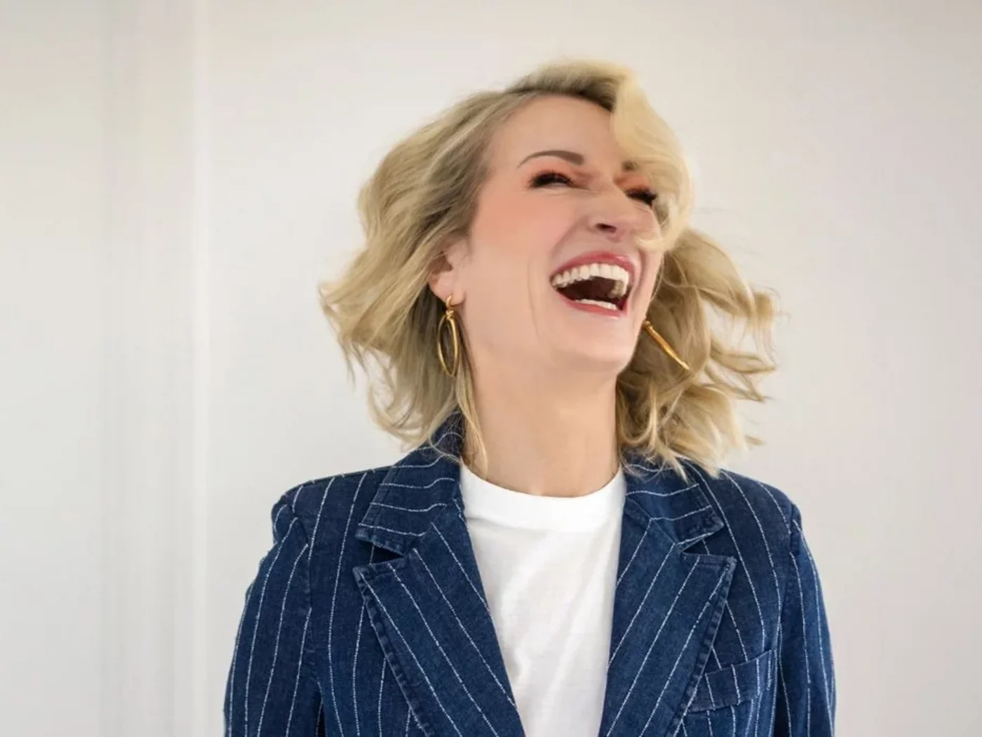 Die Schlossevents Frau mit blonden Haaren lacht laut in einem gestreiften Blazer
