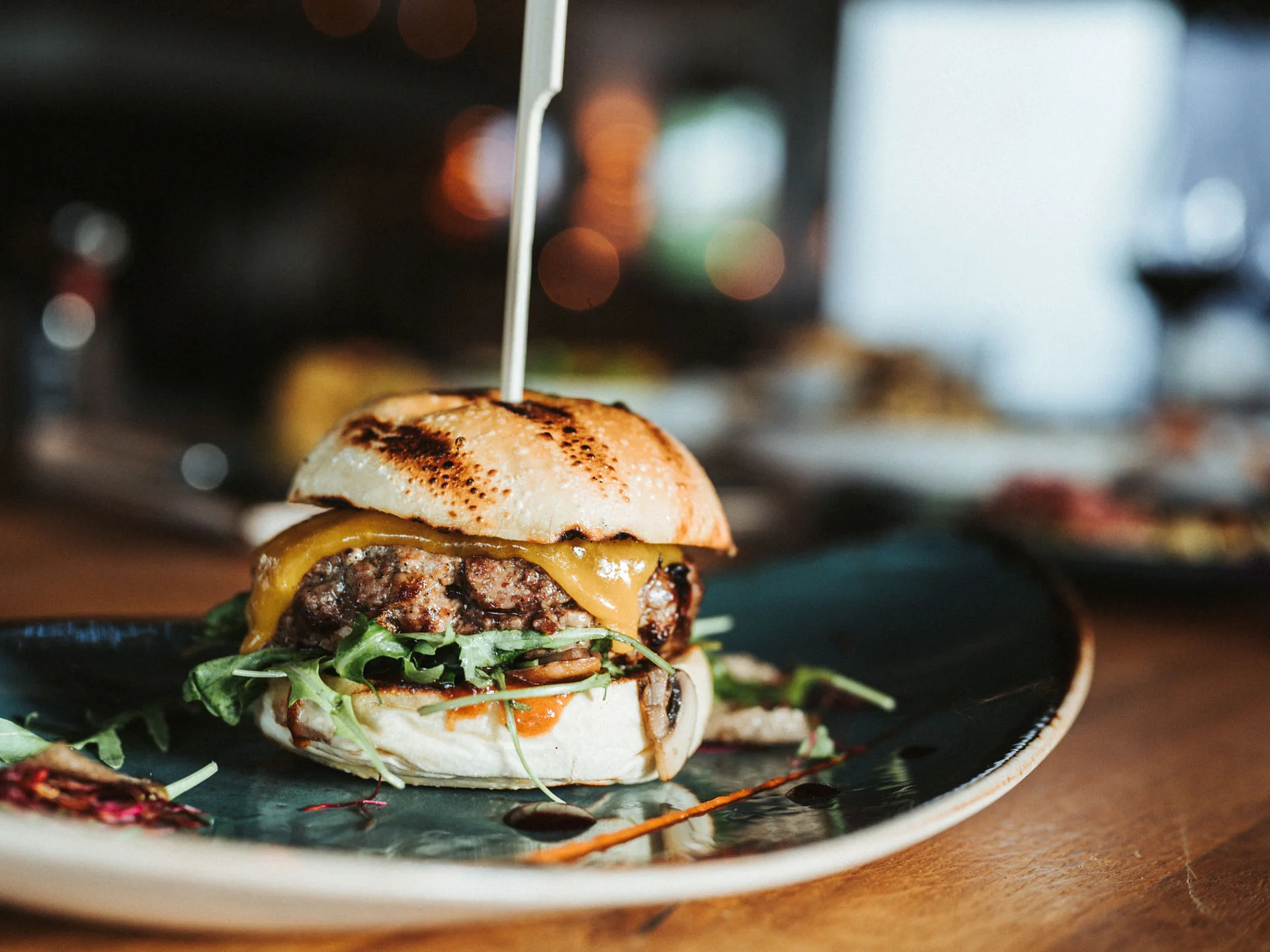 Bilder, die Sie sehen müssen. Kleiner Cheeseburger mit Salat auf einem Teller in einem Restaurant