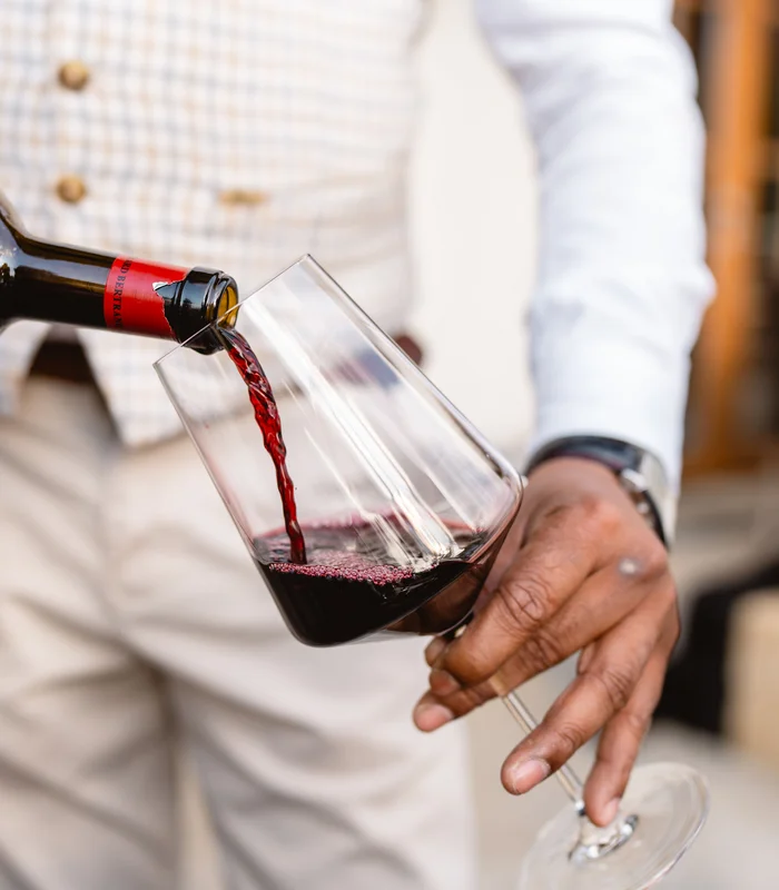 Was zählt, sind die Menschen. Person gießt Rotwein in ein Weinglas