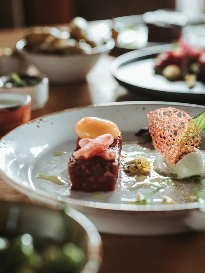 Silvester in Kitzbühel = Hotel, Party, Champagner Fein angerichtetes Gericht mit Brot und Gemüsesalaten auf Holztisch