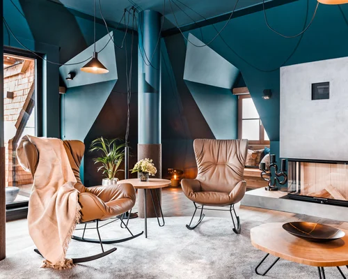 Die Schlosshotel Kitzbühel Arrangements Wohnzimmer mit modernen Schaukelstühlen, Kamin und Dekoration