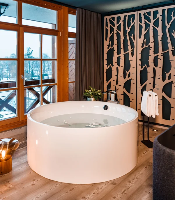 Ein Hotel mit freistehender Badewanne? Moderner runder Whirlpool in gemütlichem Raum mit Holzfenstern und Baumwanddekor