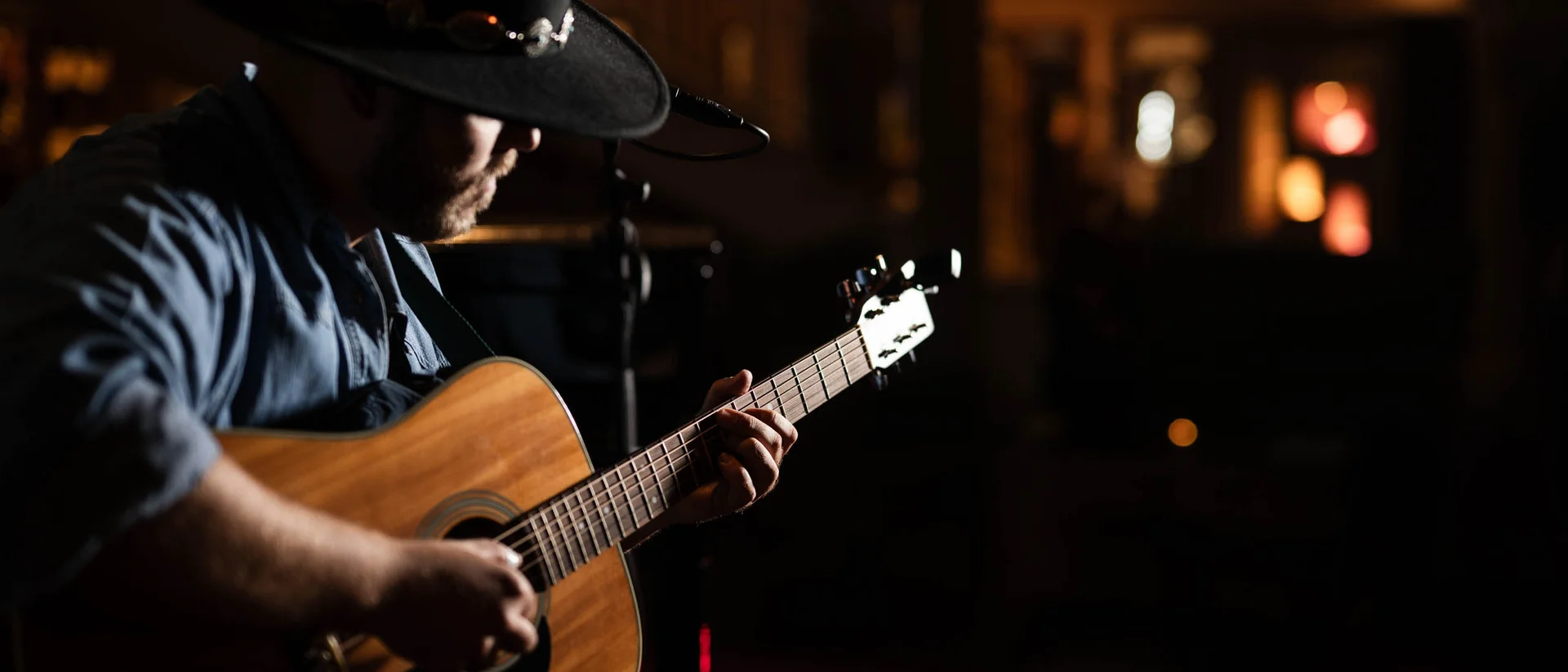 Ihr Firmenevent oder Meeting im Schlosshotel Kitzbühel Mann mit Hut spielt Akustikgitarre in dunkler Atmosphäre