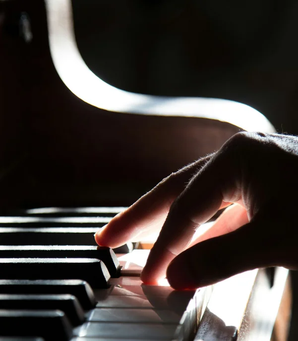 Hotel mit Klavier und Livemusik | Die Bar im Schlosshotel Kitzbühel Hand spielt Klaviertasten im Licht