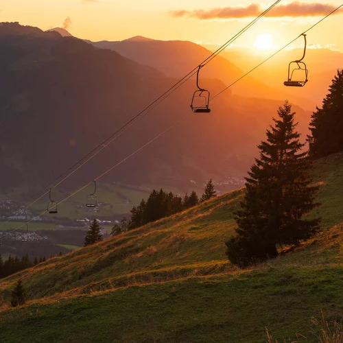 Da ist mehr drin. Sonnenuntergang über Bergen mit Sessellift und Tal darunter
