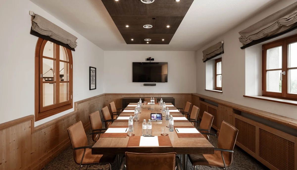 Ihr Firmenevent oder Meeting im Schlosshotel Kitzbühel Moderner Konferenzraum mit langem Holztisch und Lederstühlen