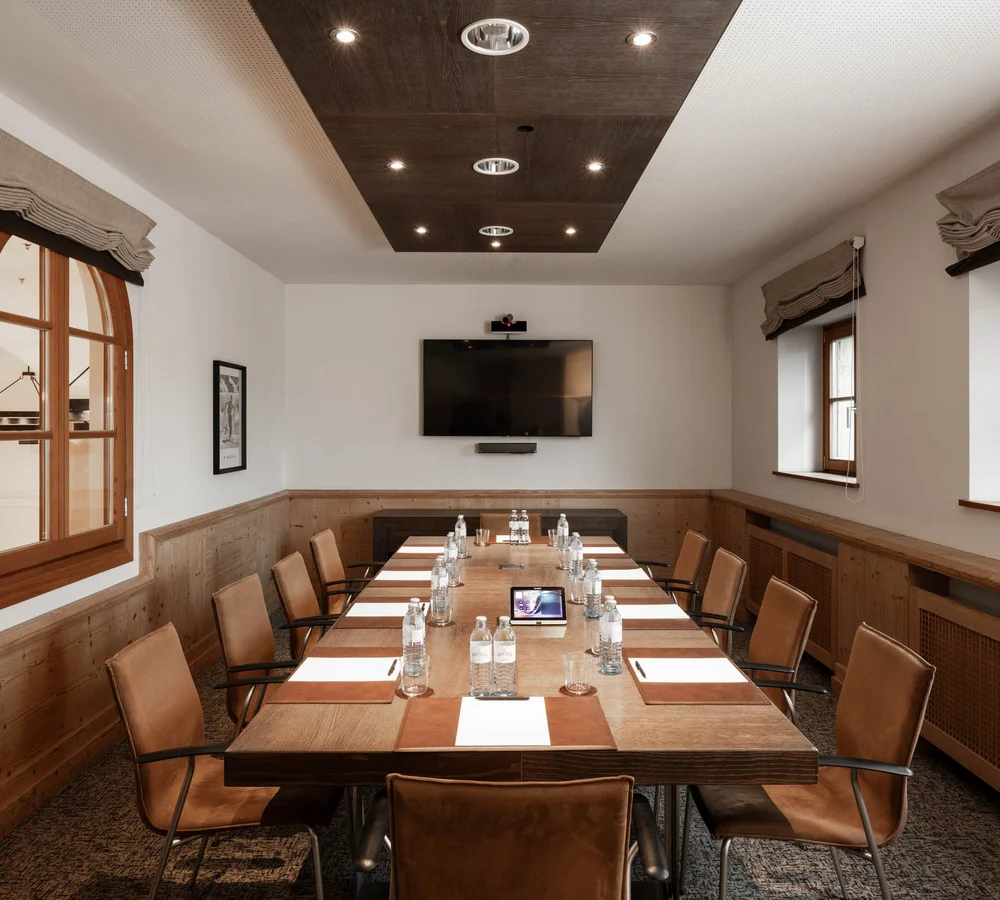 Ihr Firmenevent oder Meeting im Schlosshotel Kitzbühel Moderner Konferenzraum mit langem Holztisch und Lederstühlen