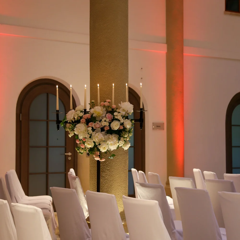 Eine der schönsten Hochzeitslocations in Tirol Weiß gedeckte Stuhlreihen und Blumenarrangements in einem festlich beleuchteten Raum