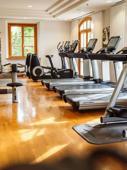 Premium-Spa im Wellnesshotel in Kitzbühel Heller Fitnessraum mit Laufbändern und Trainingsgeräten an Fenstern