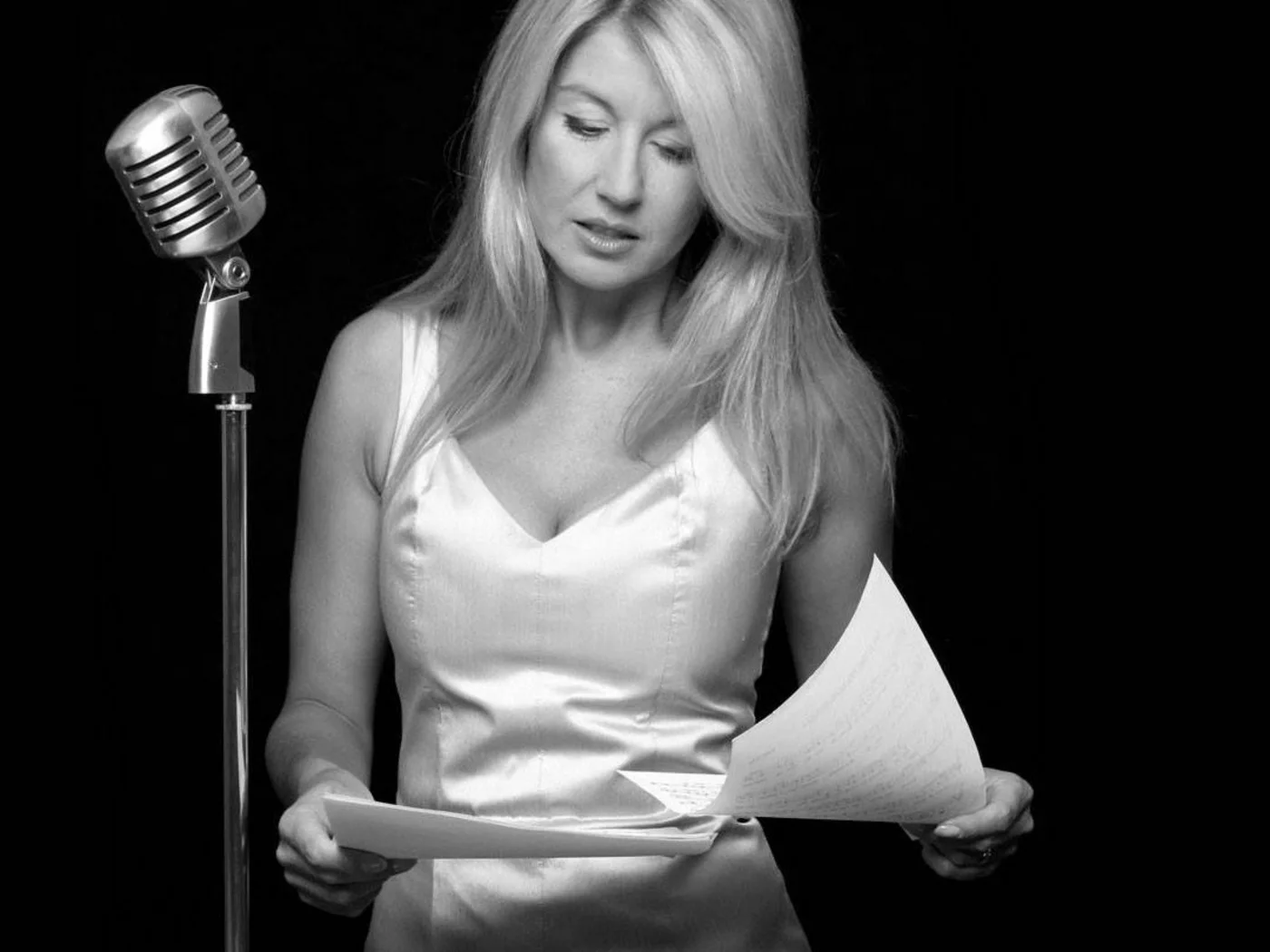 Die Schlossevents Frau mit Mikrofon liest Notenblätter vor schwarzem Hintergrund