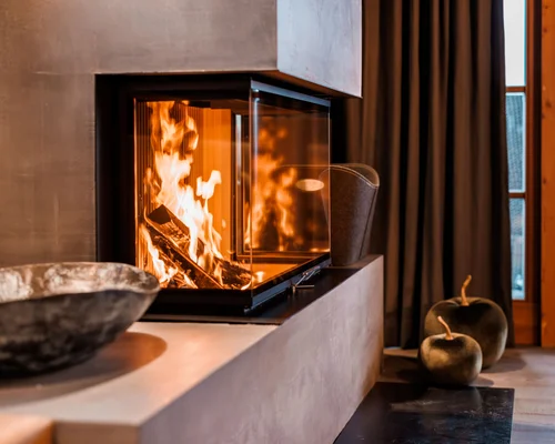 Die Schlosshotel Kitzbühel Arrangements Moderner Kamin mit brennendem Feuer in gemütlichem Wohnzimmer