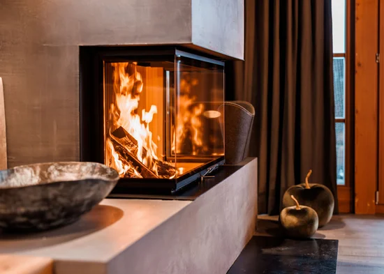 Wonach steht Ihnen heute der Sinn in Kitzbühel? Moderner Kamin mit brennendem Feuer in gemütlichem Wohnzimmer