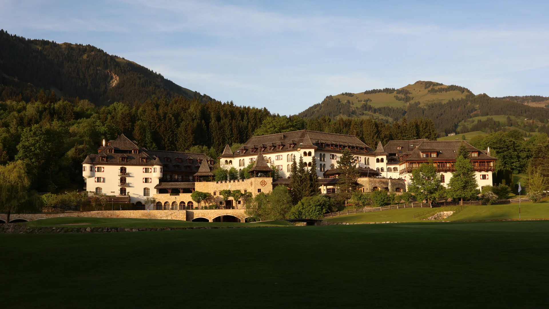 Schlosshotel Kitzbühel – ein Premiumerlebnis Hotelanlage am Fuß bewaldeter Hügel, umgeben von grünen Wiesen